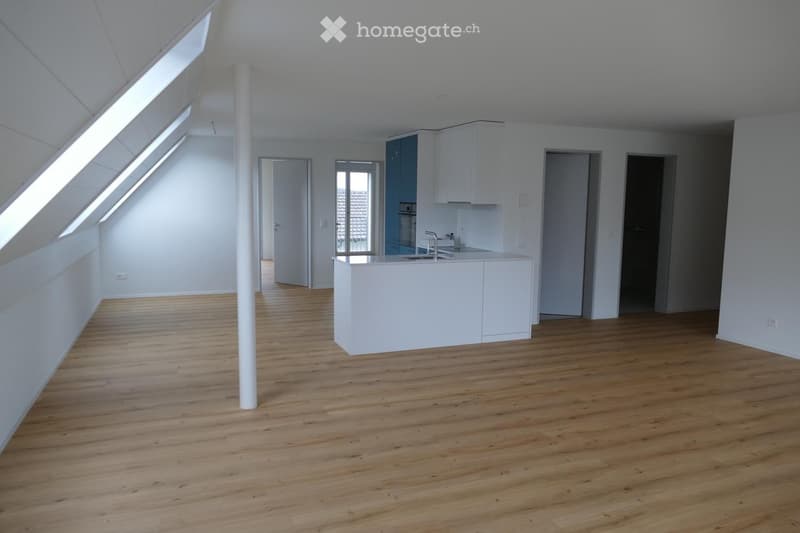 Empty kitchen with white cabinets, a central island, and wooden flooring. The space features large windows and a modern design.