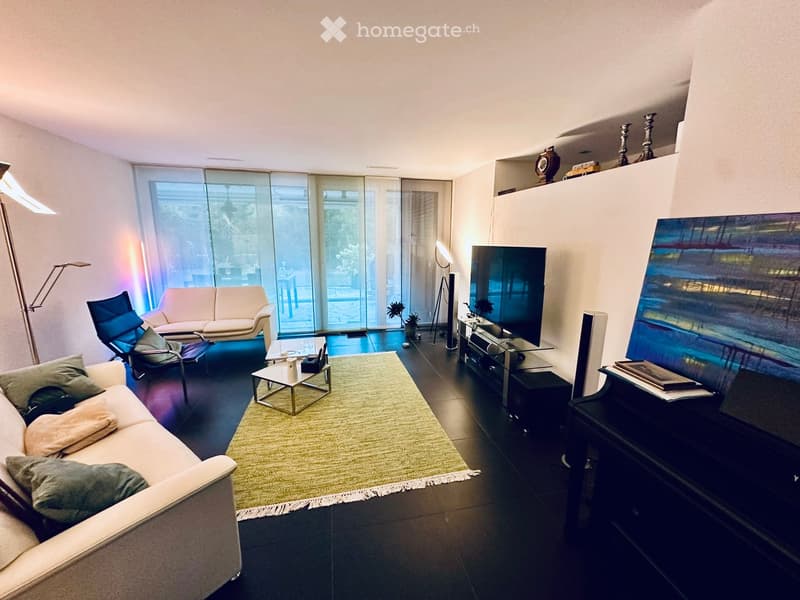 Modern living room with large glass windows, two sofas, a coffee table, a TV, and a floor lamp.