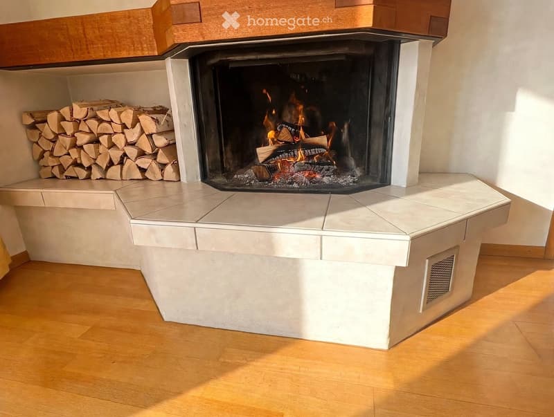 Modern living room with a built-in fireplace and a neatly stacked wood pile beside it.