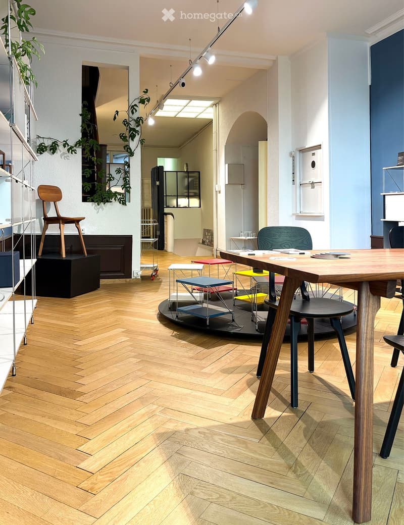 Wooden parquet floor, wooden desk, chairs, hanging lights, white walls, plants