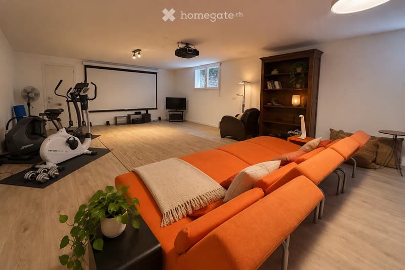 Modern living room with orange sectional sofa, coffee table, exercise bike, dumbbells, bookshelf, and projector screen.