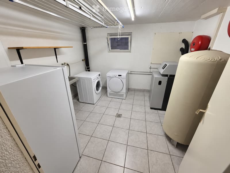 Laundry room with tiled floor, white washing machine, dryer, water heater, and a shelf.