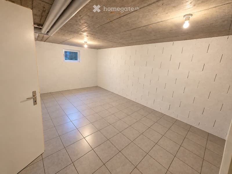 Empty room with white brick walls, tiled floor, and a small window. Exposed wooden ceiling with recessed lighting.