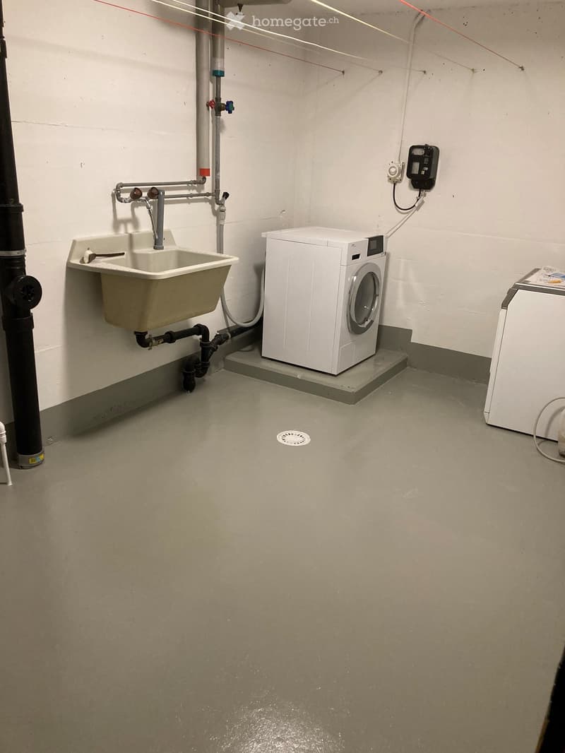 a washing machine and sink are installed on the floor of a basement