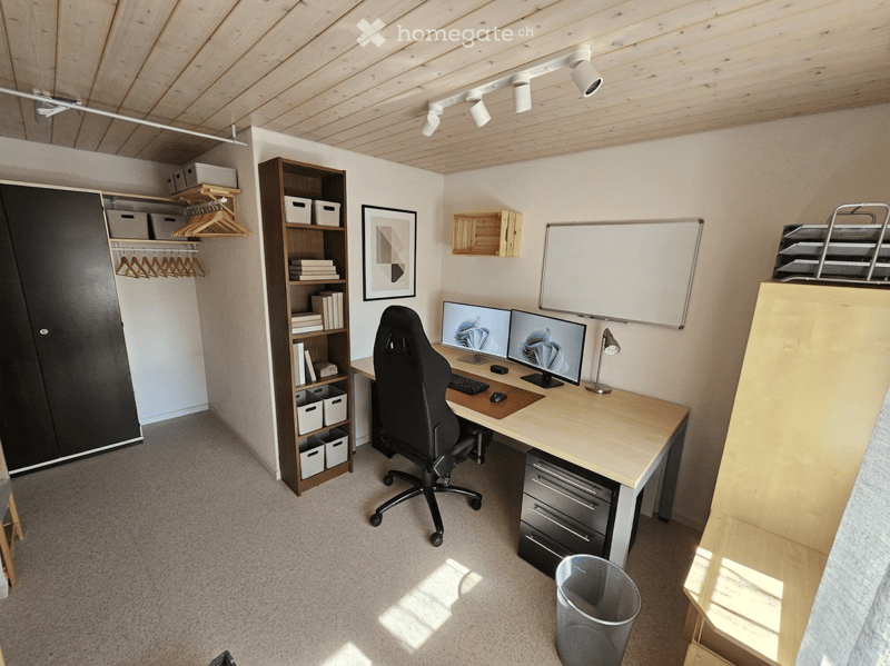 Modern, well-lit home office with a wooden ceiling, white walls, and carpeted floor. Features a large desk with dual monitors, ergonomic chair, storage cabinet, bookshelf, and whiteboard.