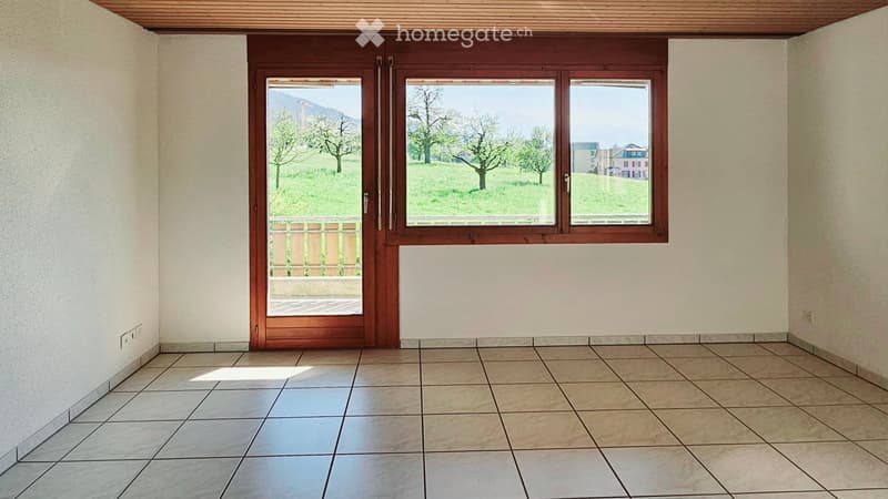 Empty room with tiled floor, large windows, and a wooden door leading to a balcony or outdoor area.