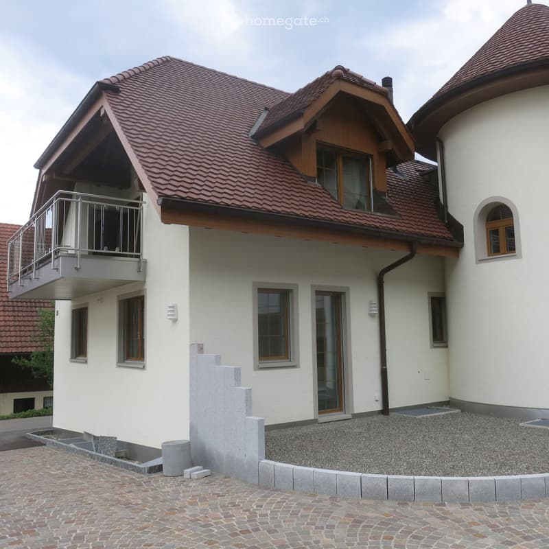 Two-story house with red-tiled roof, white exterior, multiple windows, and a balcony on the upper level.
