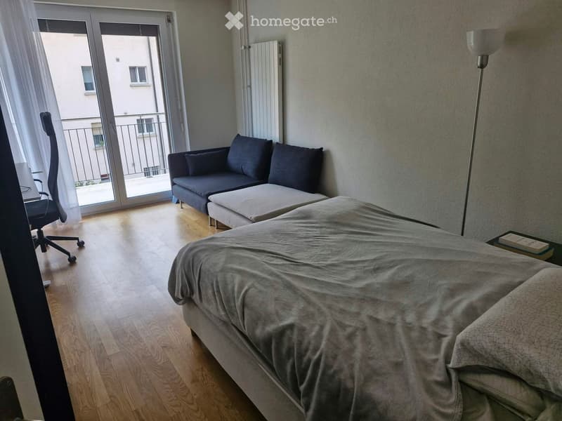 Modern bedroom with a large bed, sofa, chair, and a balcony view.