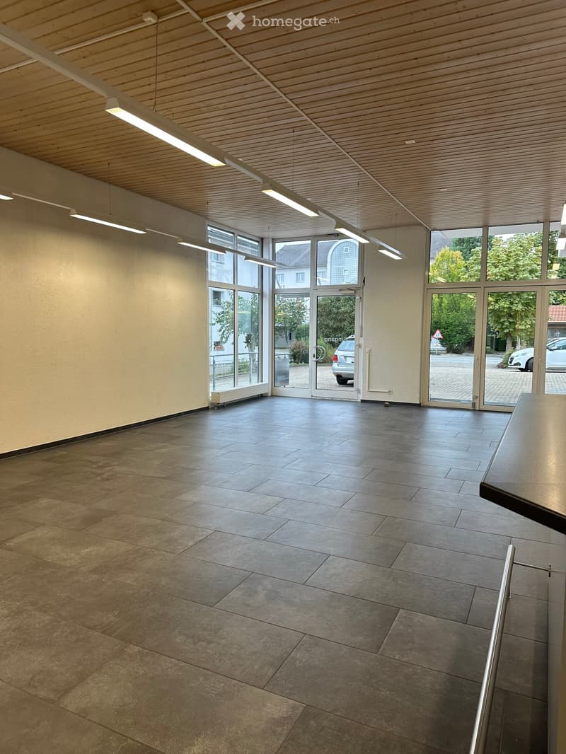 Empty room with tiled floor, large windows, and a door leading outside. No furniture or equipment present.