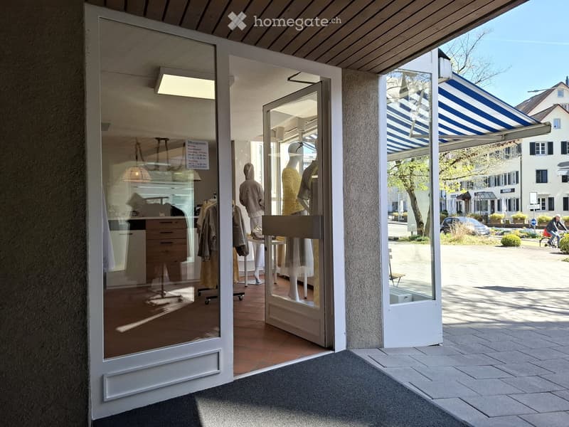 Storefront with glass doors, visible interior displays, mannequins, and lamps