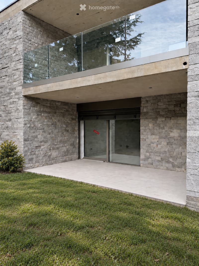 Modern two-story house with stone facade, large glass balcony, and sleek entrance door.