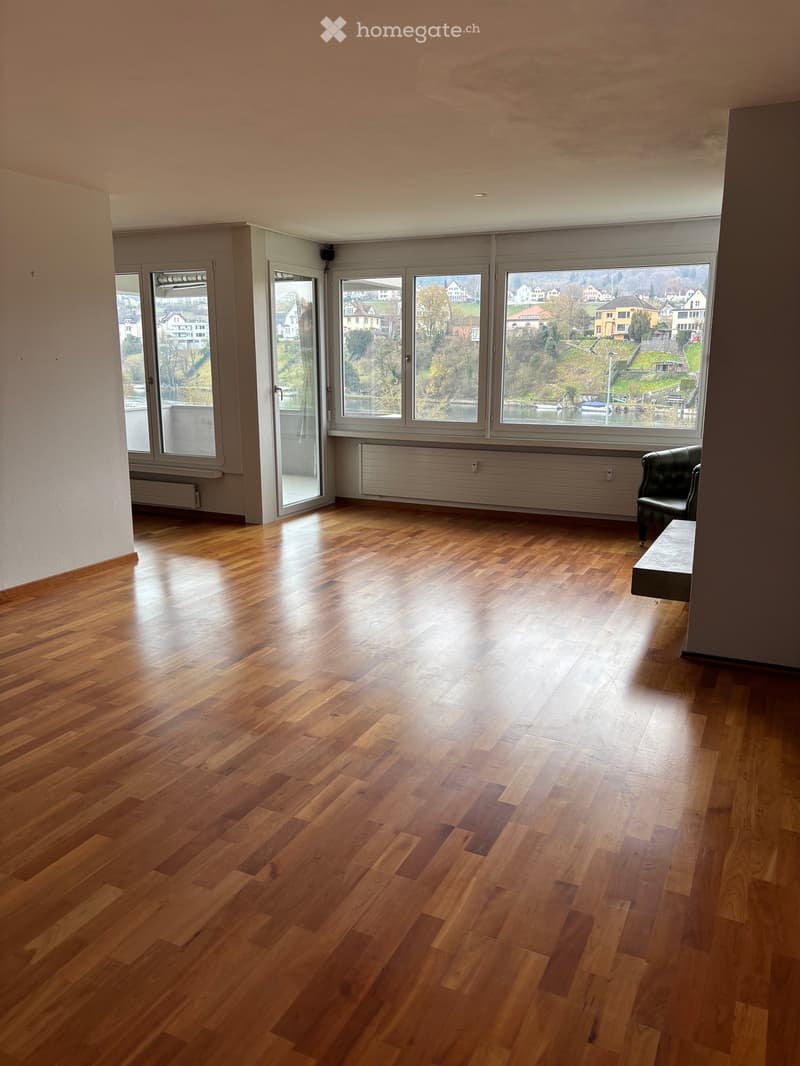 Empty room with wooden flooring, large windows, and a radiator. No furniture or equipment present.