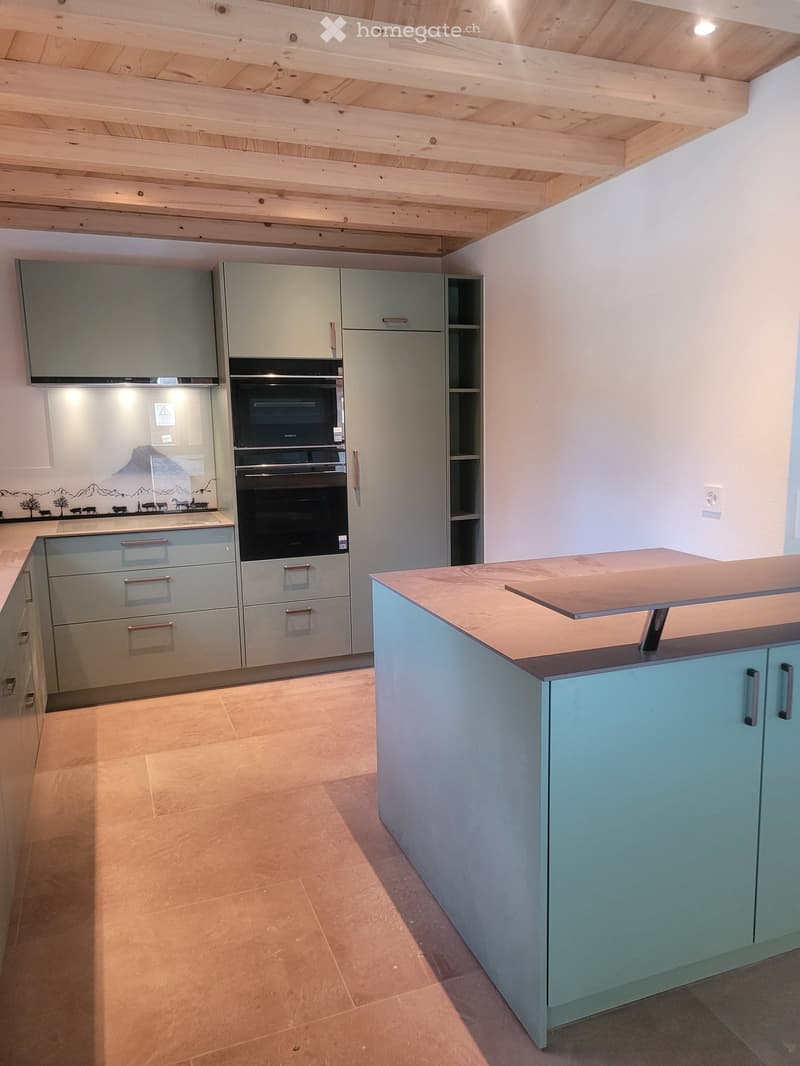 Modern kitchen with light blue cabinets, stainless steel oven, and a central island with a wooden countertop.