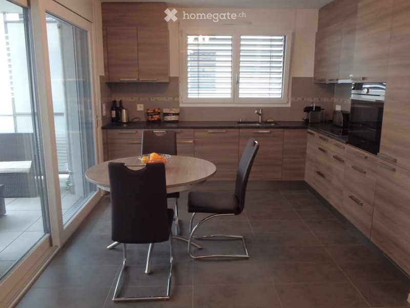Dining area with table and chairs, open kitchen, sliding door to balcony