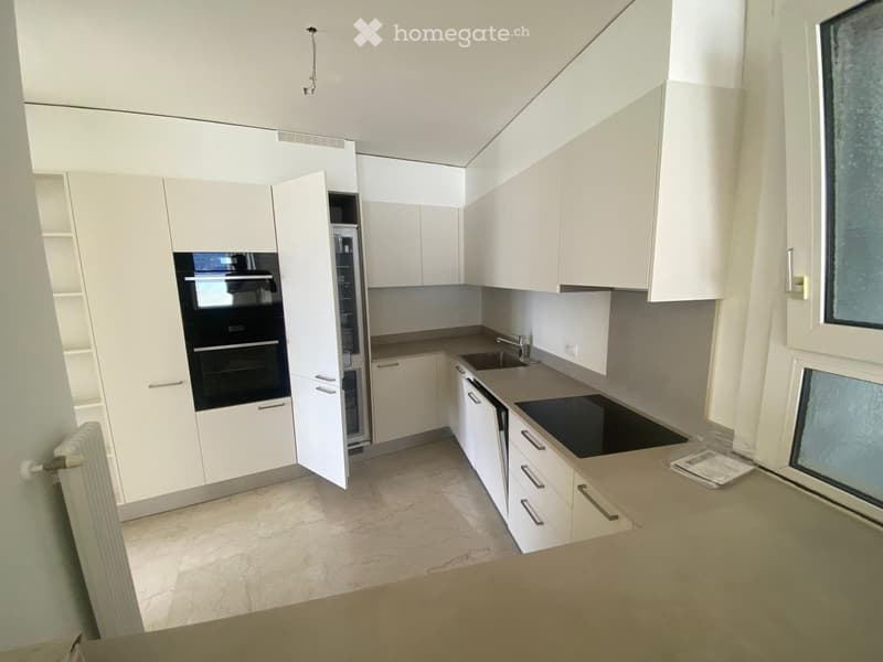 Modern kitchen with white cabinets, stainless steel appliances, and a marble floor.