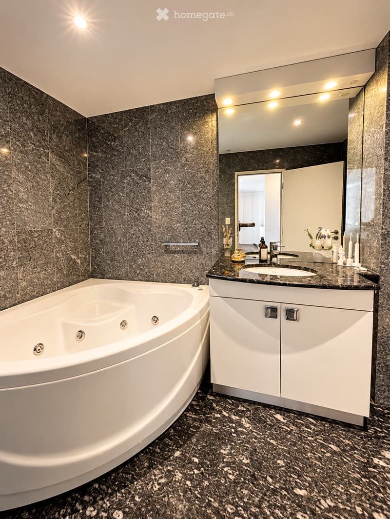 Modern bathroom with a large bathtub, double sink vanity, mirrored cabinet, and decorative items on the counter.
