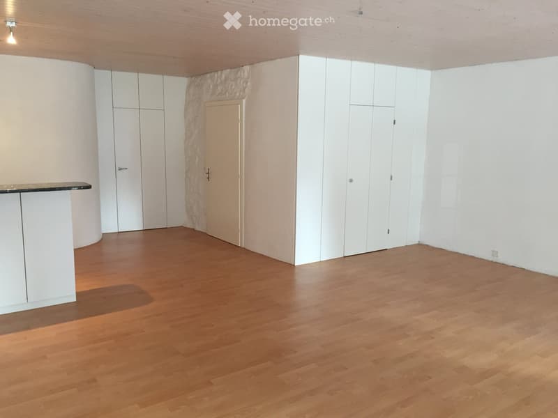 wooden floor, white walls, two white cabinets, one door, one white door, open space