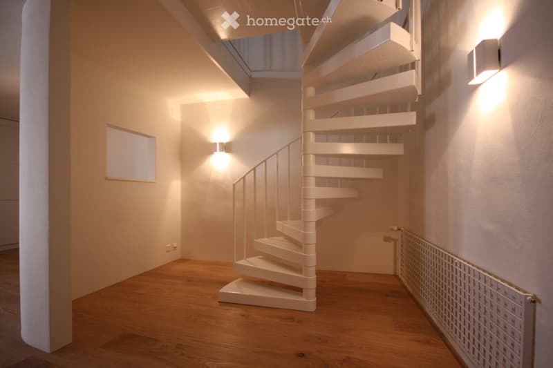 spiral staircase, wooden floor, white walls, white railing, two wall-mounted lamps