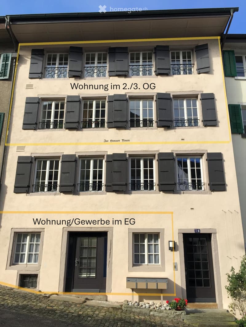 Multiple windows, balcony, main entrance on ground floor, mail boxes next to the entrance, plants at the bottom