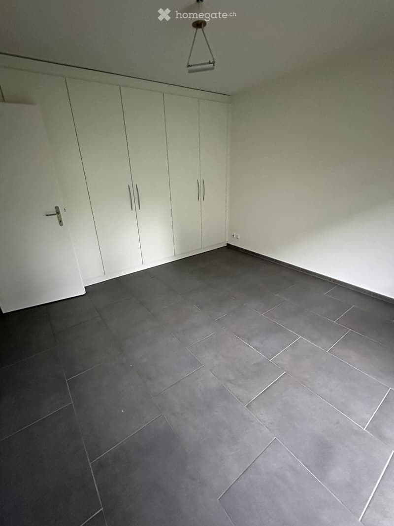 Empty room with dark grey tiled floor and white cabinetry along one wall. No furniture or equipment present.