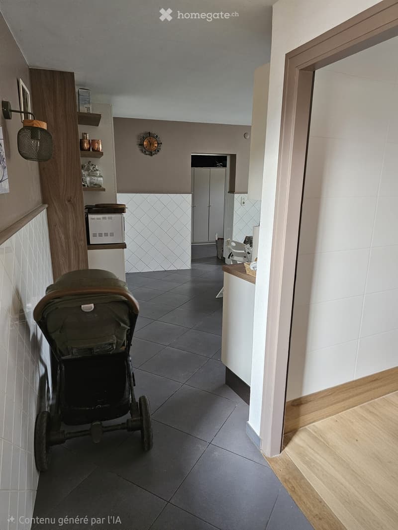 Modern hallway with grey tiled floor, white walls, wooden trim, and a stroller in the foreground. Shelves with decorative items and a small room visible at the end.