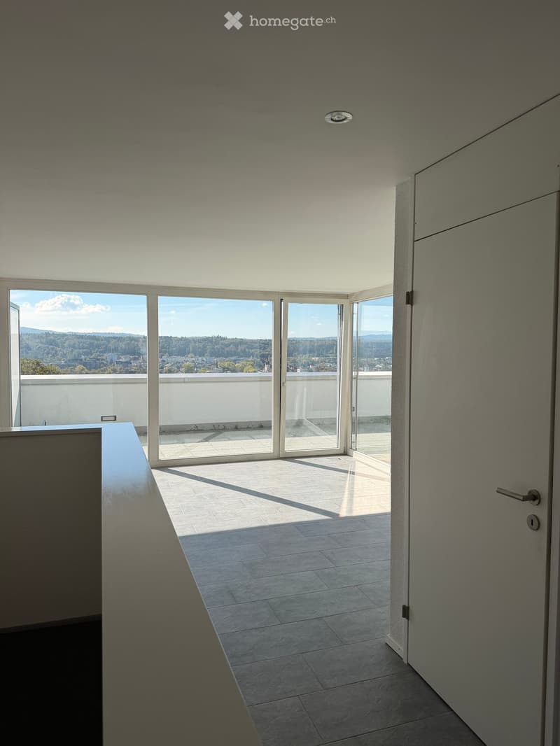 Modern hallway with large glass doors leading to a balcony, tiled floor, and minimalistic design.
