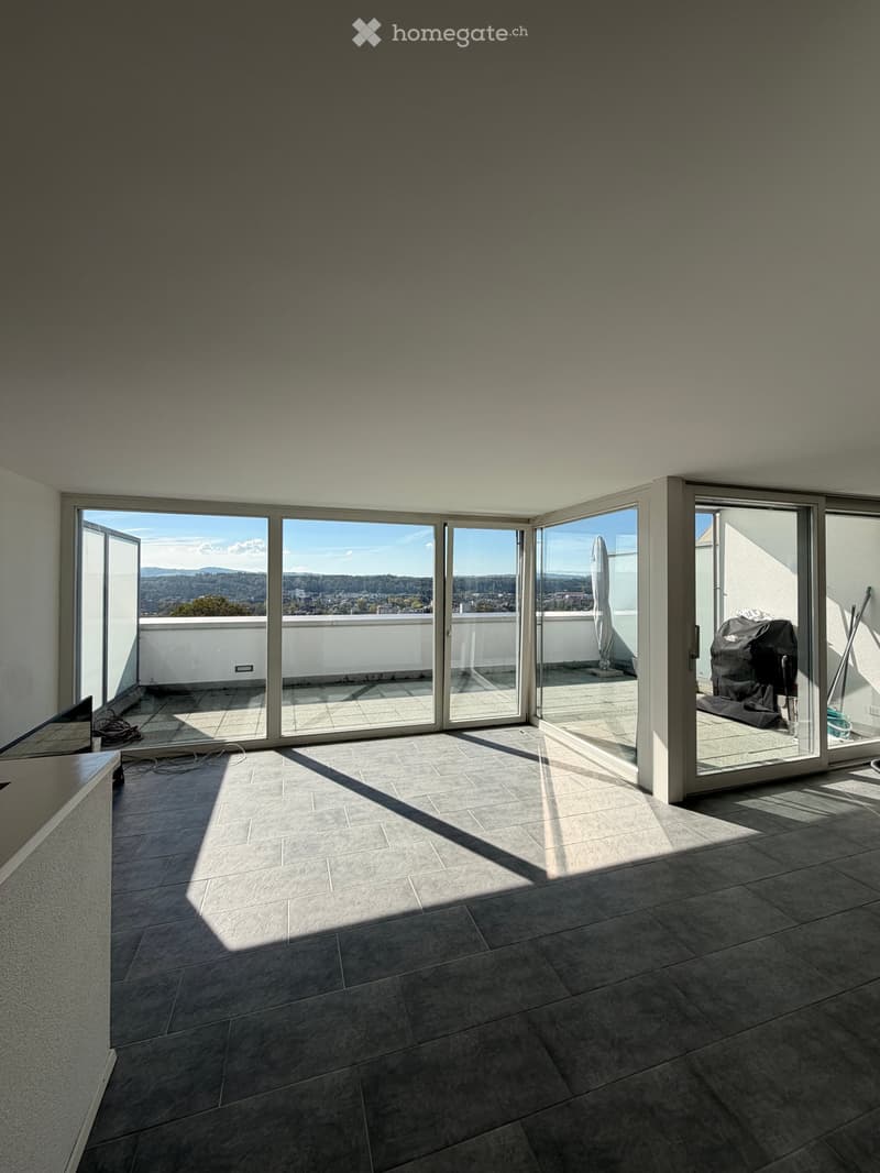 Empty room with large sliding glass doors leading to a balcony, tiled floor, and natural light.