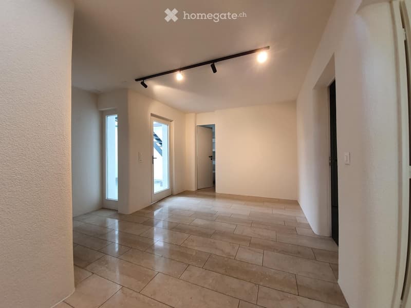 Empty hallway with tiled floor, white walls, and recessed lighting. Features a door and a window allowing natural light.