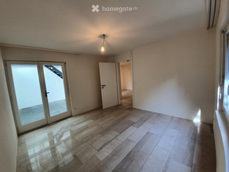 Empty room with tiled floor, white walls, and a sliding glass door leading to another space.