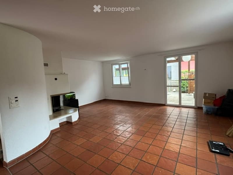 Empty room with tiled floor, white walls, a fireplace, and a sliding glass door leading to a balcony.