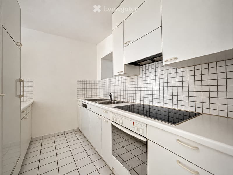 Modern kitchen with white cabinets, tiled backsplash, and stainless steel appliances including a sink, stove, and oven.