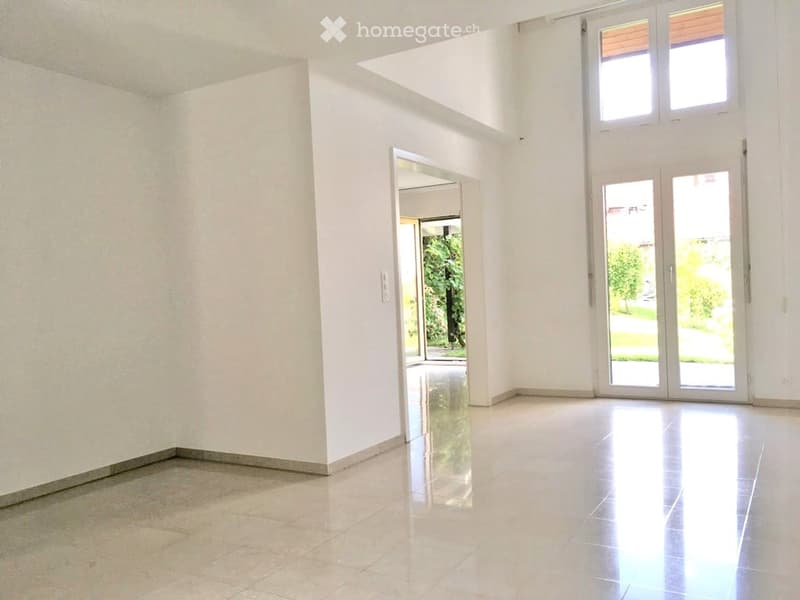 Empty room with white walls, polished tile floor, large windows, and open doors leading to an outdoor area.