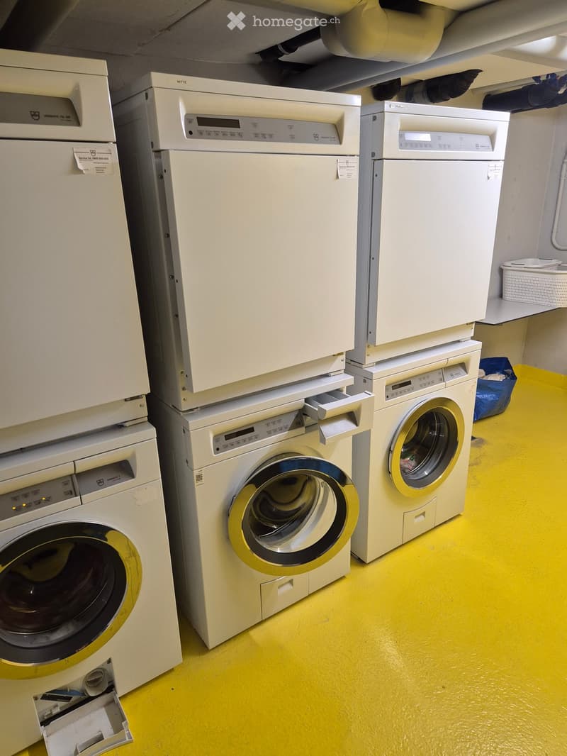 A room with multiple stacked washing machines and dishwashers, yellow flooring, and white walls.