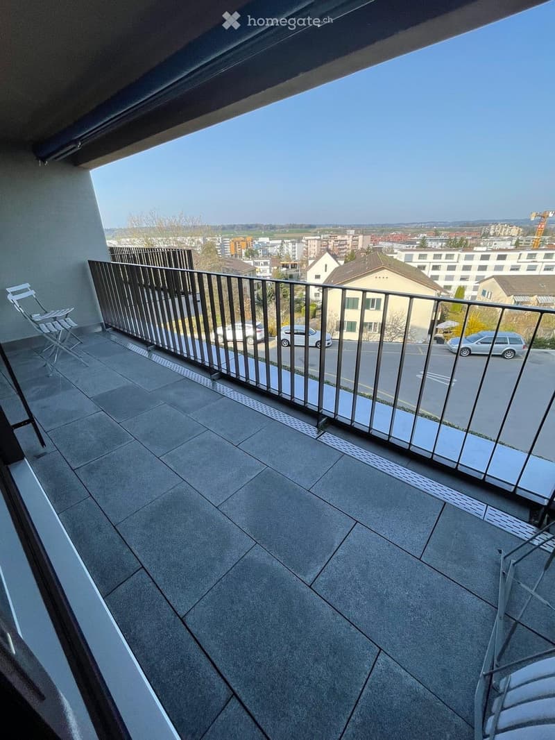 Balcony with tiled floor, metal railing, and a view of the cityscape and surrounding buildings.