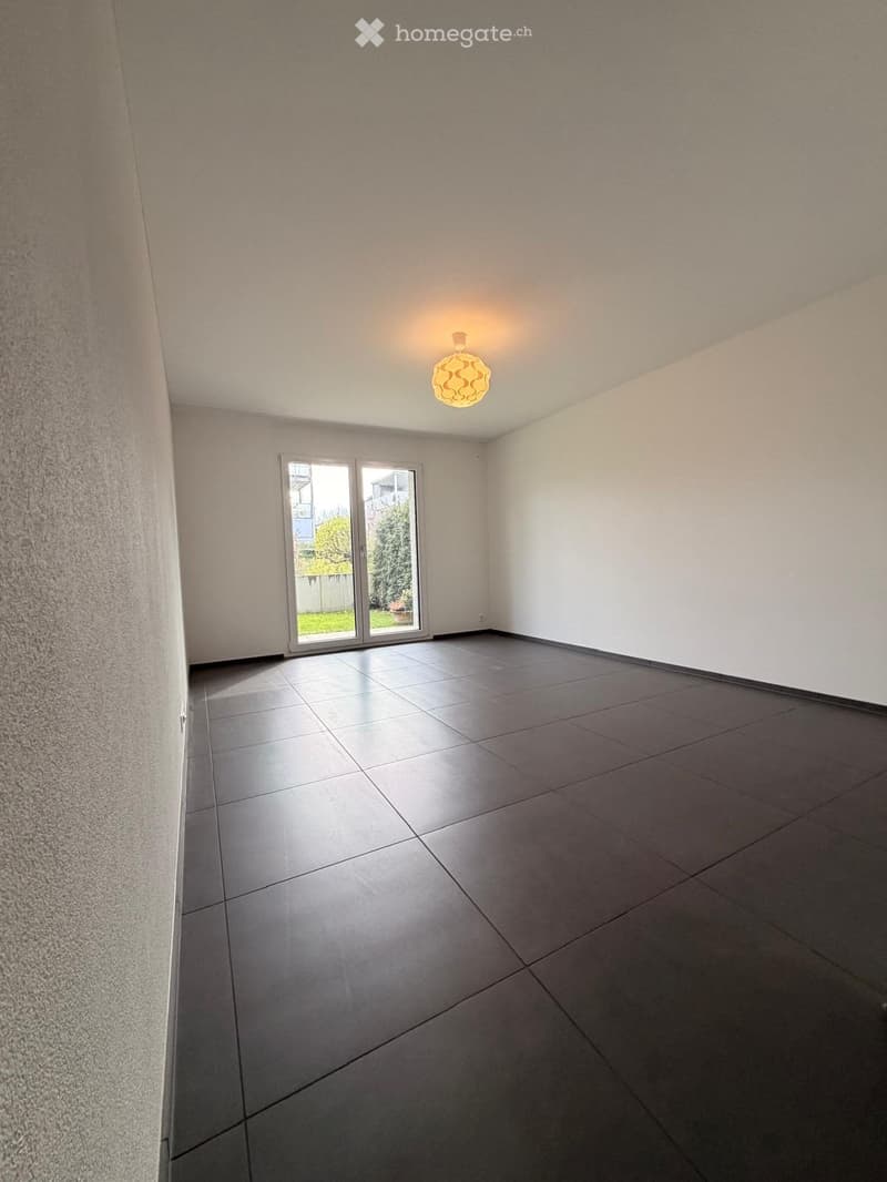 Empty room with tiled floor, white walls, and a large sliding glass door leading to an outdoor area.