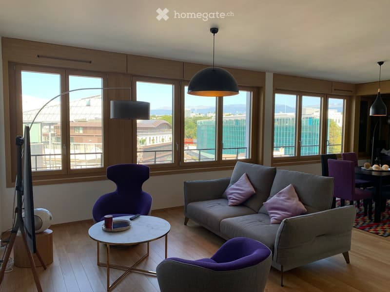Modern living room with large windows offering a city view, featuring a grey sectional sofa with pink pillows, a round marble coffee table, purple accent chairs, and a sleek floor lamp.