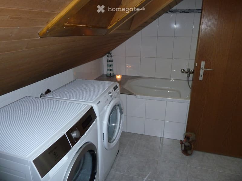 Bathroom with a washing machine, bathtub, candle, and a small decorative lantern on the counter.