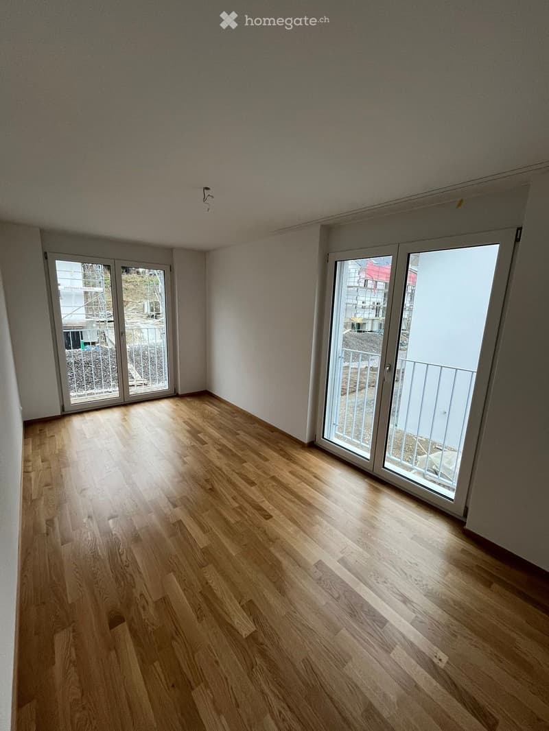 Empty room with wooden flooring and large sliding glass doors leading to a balcony.