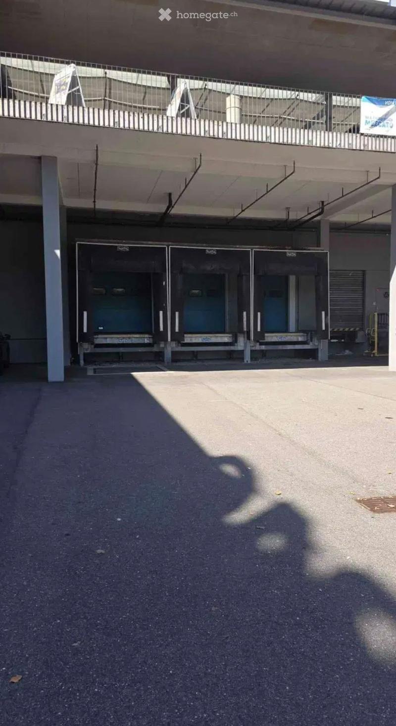 Multi-level parking structure with three garage doors and a metal railing on the upper level.