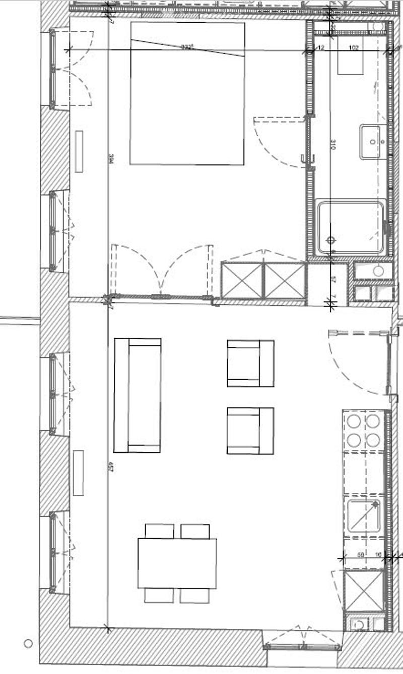 Floor plan of a residential space featuring a living room, dining area, kitchen, bedroom, and bathroom. The layout includes a central living space with a dining table and chairs, a kitchen area with cabinets and appliances, a bedroom with a bed, and a bat
