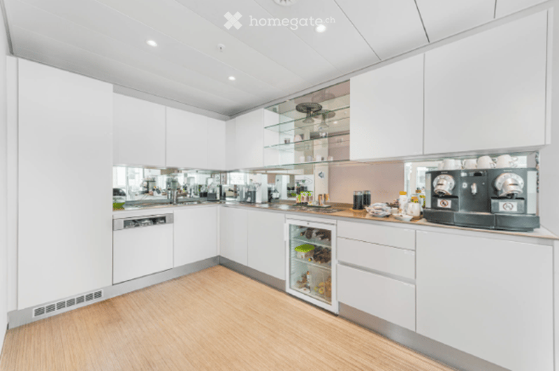 Modern, minimalist kitchen with white cabinets, a built-in dishwasher, a small refrigerator, and a coffee machine on the counter.