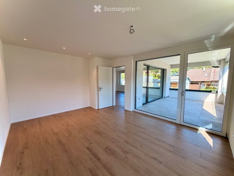 Empty room with wooden flooring, white walls, and large sliding glass doors leading to a balcony.