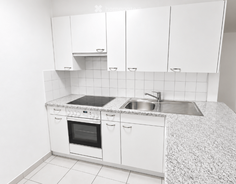 Modern kitchen with white cabinets, granite countertop, induction cooktop, oven, and stainless steel sink.