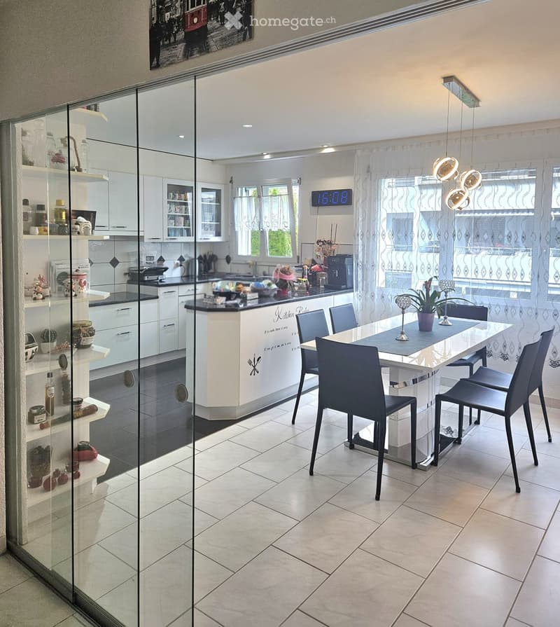 Modern kitchen with white cabinets, black countertops, and a dining area with a white table and black chairs.