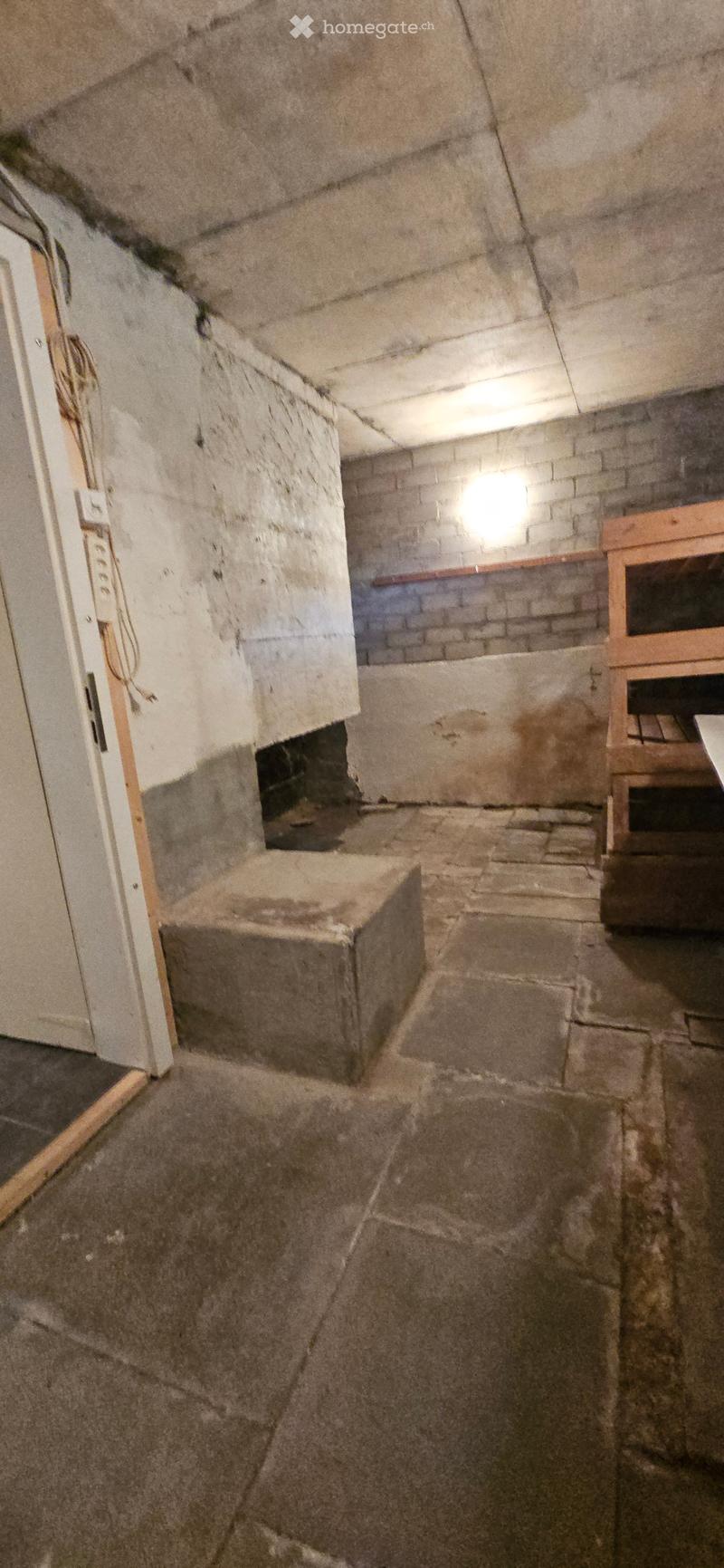 Empty basement space with stone walls, concrete floor, and exposed wooden beams. No furniture or equipment present.