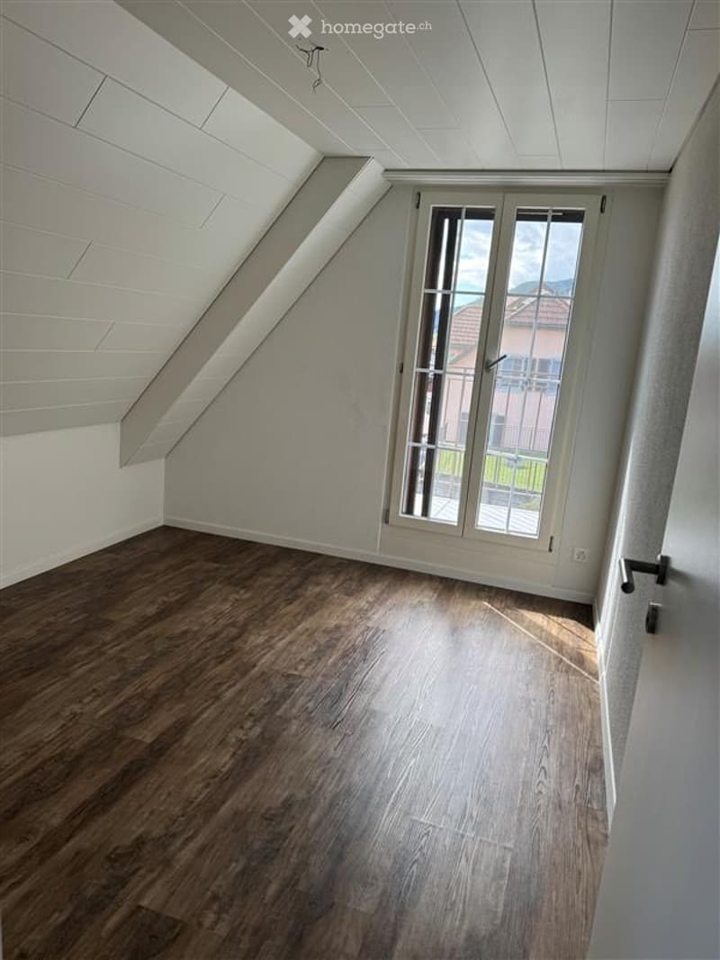 an empty attic room with hardwood floors and a large glass window that leads to a balcony