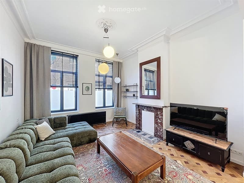 Modern living room with a sectional sofa, coffee table, armchair, TV, fireplace, and large windows with curtains.