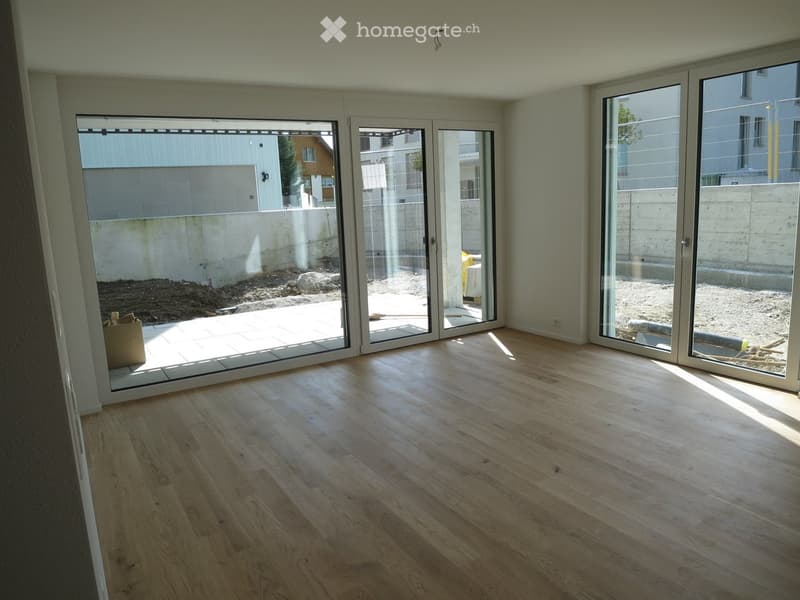 Empty room with light wooden flooring and large sliding glass doors leading to an outdoor area.