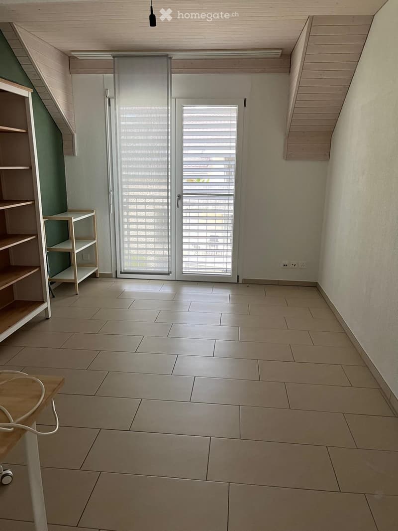 Empty room with tiled floor, wooden shelving unit, and large sliding glass door with blinds.