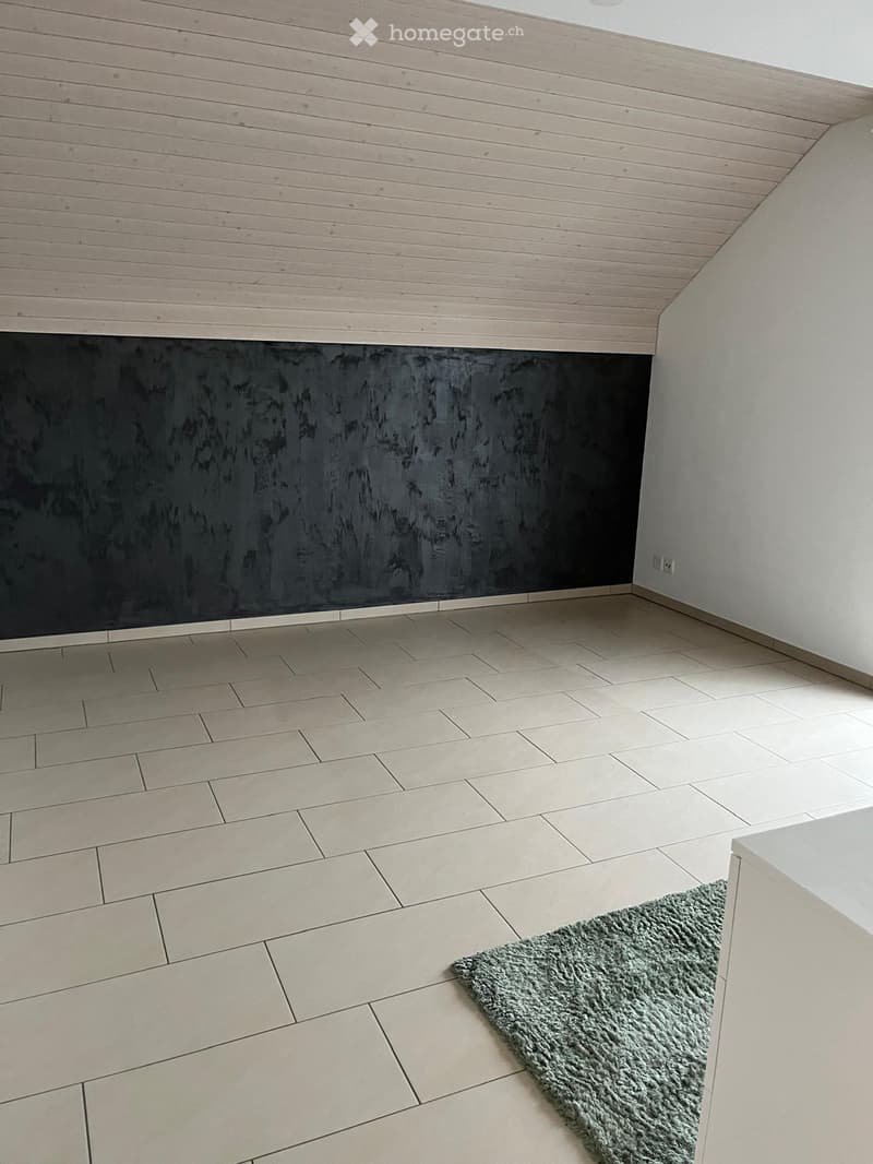 Empty room with tiled floor, light-colored walls, and a small green rug in the corner.